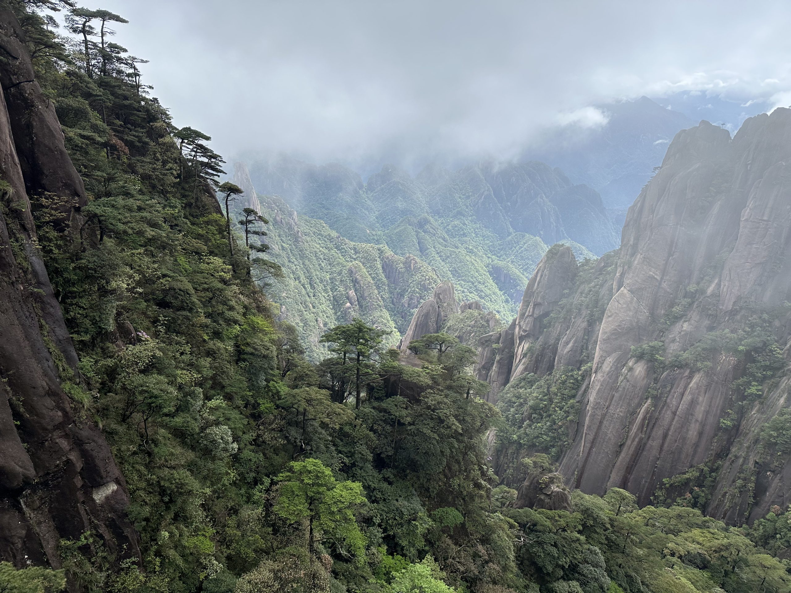 A green mountain valley and granite cliffs beneath low cloud